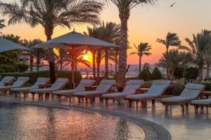 a pool with chairs and umbrellas at sunset at Cleopatra Luxury Resort Sharm El Sheikh in Sharm El Sheikh
