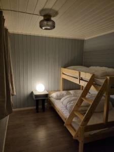 a bedroom with a bunk bed and a table with a light at Off-the-grid cabin on the island of Senja in northern Norway in Brygghaugen