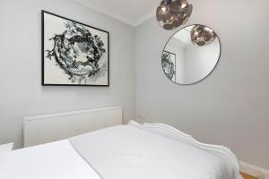 biała sypialnia z łóżkiem i lustrem w obiekcie PenthouseStays Notting Hill - Spacious 3 Bedroom King Bed Apartment - near Portobello Road & Kensington High Street w Londynie