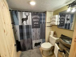 ein Badezimmer mit einem Duschvorhang, einem Reh und einem Waschbecken in der Unterkunft Cozy Creekside cabin- 35m to Boone in Butler