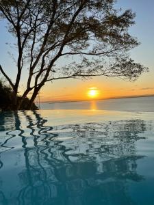 una piscina de agua con una puesta de sol en el fondo en Casa con increible vista, en Morro de São Paulo