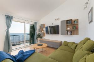 a living room with a green couch and a large window at Apartment by the sea in Podgora