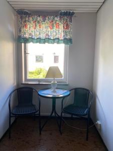 two chairs and a table with a lamp and a window at Vandrarhem Oden in Odensbacken