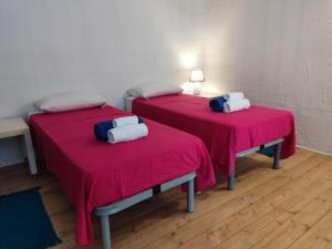 2 Betten in einem Zimmer mit rosa Bettwäsche in der Unterkunft Casa Cubino in Gioiosa Marea