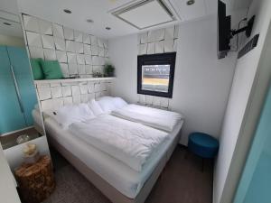a small bed in a small room with a window at Hausboot Lobster Bremerhaven in Bremerhaven