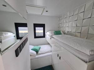 a small room with a bed and two windows at Hausboot Lobster Bremerhaven in Bremerhaven