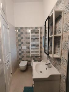 La salle de bains est pourvue d'un lavabo blanc et de toilettes. dans l'établissement La Liama di CasAda, à Spongano