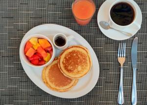 einen Teller mit Pfannkuchen und Obst und eine Tasse Kaffee in der Unterkunft Hotel Giada in Sámara