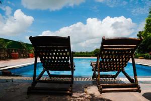 two chairs sitting next to a swimming pool at The Rustic Villa, a stay with luxuries amenities and exotic nature in Jaipur