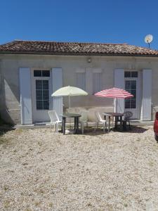 dos mesas y sillas con sombrillas frente a una casa en Appartements Danciu, en Jonzac
