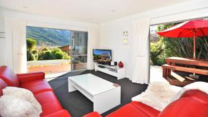 a living room with red furniture and a red umbrella at Holiday home Queen Charlotte in Anakiwa