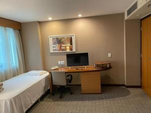 Ibirapuera hotel 5 estrelas 2 suites في ساو باولو: غرفة نوم بها مكتب وبه جهاز كمبيوتر