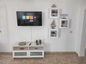 a white entertainment center with a flat screen tv on a wall at Casa de los pajaritos. in Charco del Palo