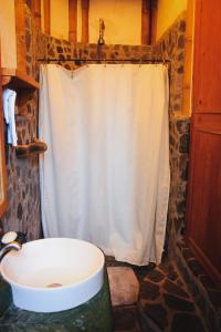 a bathroom with a white shower curtain and a sink at Bambu Guest House in Tzununá