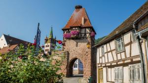 un antiguo edificio con una torre con flores. en Chambre spacieuse dans joli village alsacien en Châtenois