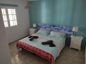 een slaapkamer met een groot bed met 2 nachtkastjes bij Casa de los pajaritos. in Charco del Palo