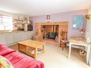 a living room with a red couch and a fireplace at Willow Cottage in Norwich