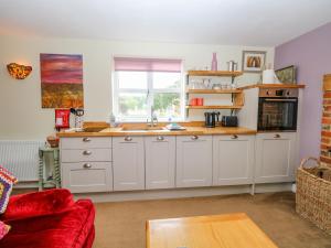 una cocina con armarios blancos y fregadero en Willow Cottage en Norwich