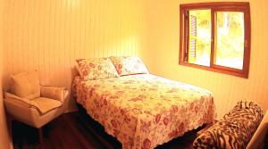 a bedroom with a bed and a chair and a window at Cabana das Montanhas in Caxias do Sul