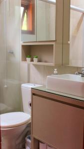 een badkamer met een wastafel, een toilet en een spiegel bij Cabana das Montanhas in Caxias do Sul