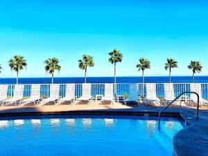 a swimming pool with palm trees and the ocean at Sunrise Bliss Villa in Avalon