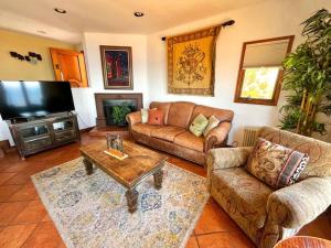 a living room with couches and a table and a tv at Sunrise Bliss Villa in Avalon