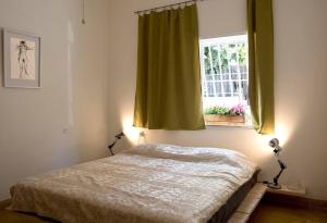 CHARMING APARTMENT AT UNBEATABLE SPOT في تل أبيب: غرفة نوم بسرير ونافذة مع ستائر خضراء