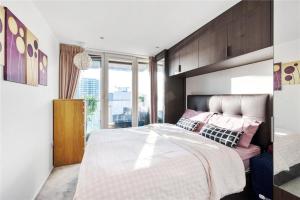 ロンドンにあるTwo Bedroom Apartment - London ExCeL Staysのベッドルーム1室(ピンクの枕が付いた大型ベッド1台付)