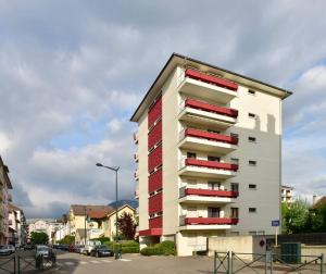 a tall apartment building with red and white windows at Cabana & Le Central - Proche Lac , Terrasse et Parking in Annecy