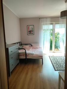 a bedroom with a bed with a dresser and a window at Domek Mordarka in Limanowa
