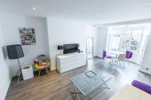 un salon avec une télévision et une table dans l'établissement Paddington/Lancaster Gate Luxury Apartment by Hyde Park, à Londres