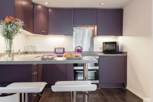 une cuisine avec des placards violets et un comptoir dans l'établissement Paddington/Lancaster Gate Luxury Apartment by Hyde Park, à Londres