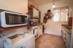 a kitchen with a microwave and a stove at Casa Fuchsia Régia em Rancho Queimado/SC in Rancho Queimado