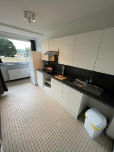 uma cozinha com armários brancos e piso em azulejo em Alexis's loft em Liège