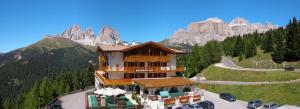 un edificio in montagna con macchine parcheggiate intorno di Hotel Bellavista a Canazei