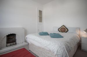 a white bedroom with a bed with a fireplace at Ty Golau - 3 Bed Holiday Home - Pembroke in Pembroke