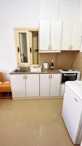 a kitchen with white cabinets and a white refrigerator at Ksamildream in Ksamil