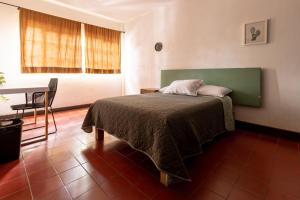 a bedroom with a bed with a green headboard and a table at Casa Sabina in Guadalajara