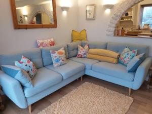 um sofá azul com almofadas numa sala de estar em Hidden gem on the edge of the Cotswolds em Charfield