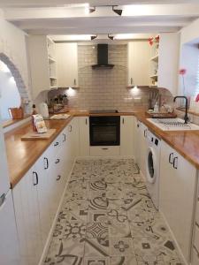 a kitchen with white cabinets and a tile floor at Hidden gem on the edge of the Cotswolds in Charfield