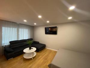 a living room with a black couch and a table at Feelings Apartment apartamenti Smiltene in Smiltene