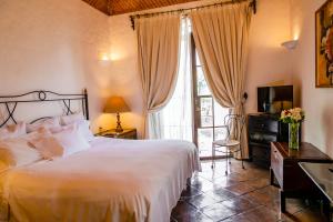 a bedroom with a bed and a television and a window at Villa Ganz Boutique Hotel in Guadalajara