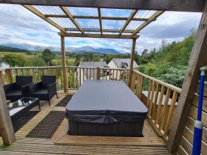 a bed on a wooden deck with a pergola at Nadurra But and Ben - Where the Ordinary Becomes Extraordinary in Fort William