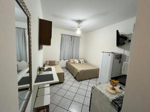 ein kleines Wohnzimmer mit einem Bett und einem Kühlschrank in der Unterkunft KITNET ACONCHEGANTE A 3 MINUTOS DA PRAIA in Guarapari