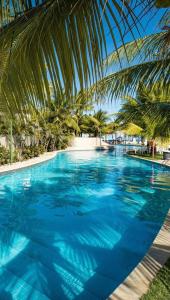 uma grande piscina com água azul e palmeiras em Beach Class Park 02 Quartos em Porto de Galinhas