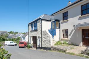 a white house with blue windows and a driveway at The Lookout - A Great Adventure in Kingsbridge