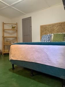Cama grande en habitación con suelo verde en Chirris Hostel, en San Juan La Laguna