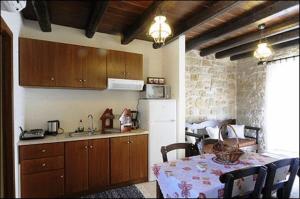 a kitchen with a table and a white refrigerator at Esperides Stone Houses in Palekastron