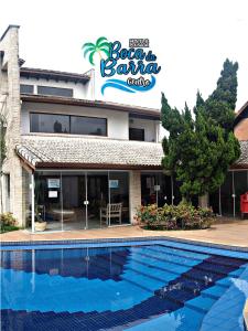 a hotel with a swimming pool in front of a building at Pousada & Hostel Boca da Barra in Itanhaém