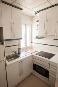 a kitchen with white cabinets and a sink and a stove at Cozy house near to the city center of Granada in Granada